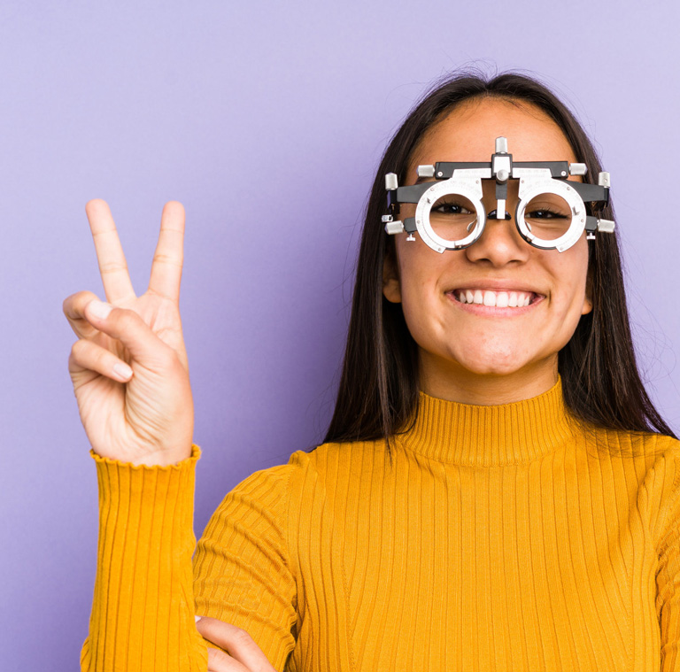 A young woman wearing eye test glasses and making a peace sign.