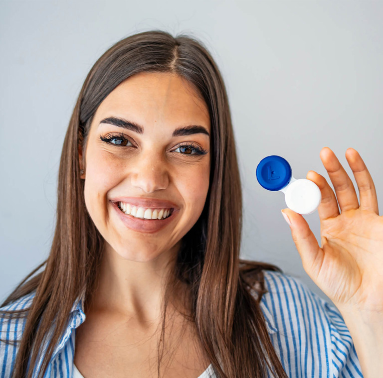 a woman holding a container of contact lenses